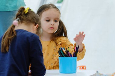 Renkli kalemle resim yapan Avrupalı tatlı bir kız. Anaokulu çocuk eğitim konsepti.