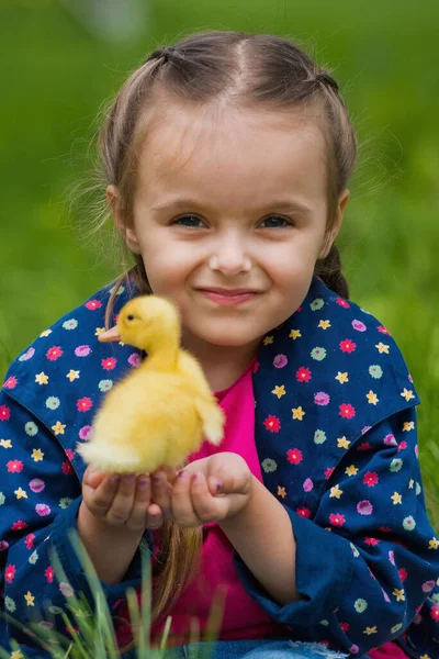 stock image Cute happy little girl with of small duckling in the garden. Little girl holding a duckling in her hands.