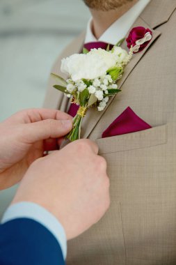Damat ceketindeki yaka çiçeğini tamir ediyor. Yüzü yok. Seçici odak.