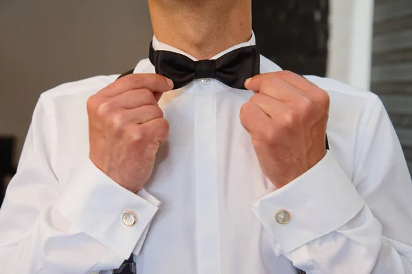 Man fixing his bow tie. Man groom in wedding suit with a bow tie. Close-up.