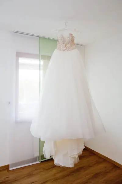 The delicate bride\'s dress is hanging in room. Selective focus.