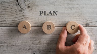A, B ve C harfleriyle ahşap kesim çemberleri beyaz ahşap arka planda bir Plan işareti altında. 