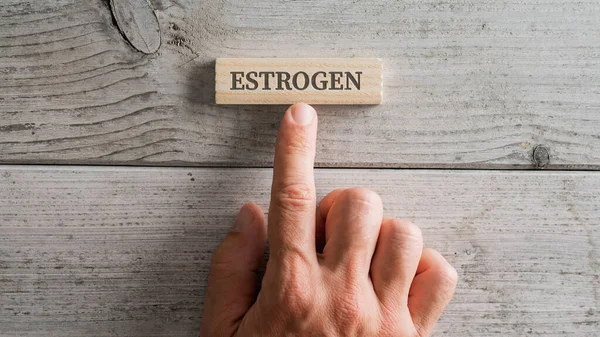 Male Hand Placing Wooden Peg Estrogen Sign White Wooden Background — Stock Photo, Image