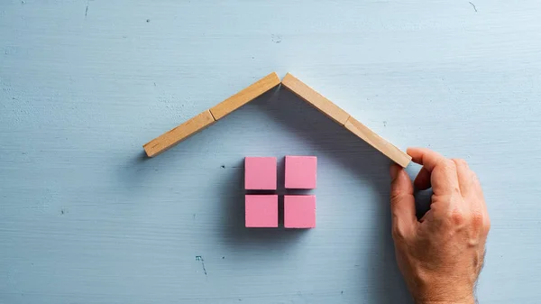 Männliche Hand Baut Ein Haus Aus Rosa Holzklötzen Auf Pastellblauem — Stockfoto