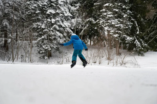 穿着蓝色冬衣的孩子们在雪白冬日的自然冰上滑冰 — 图库照片