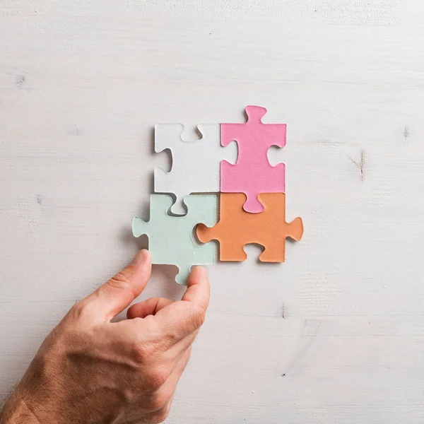 Top View Male Hand Joining Four Matching Colorful Puzzle Pieces — Stock Photo, Image
