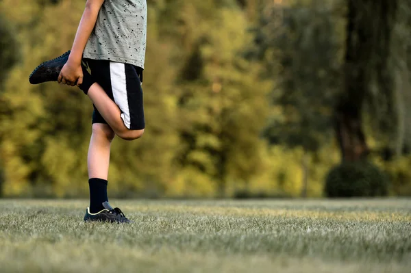 Criança Aquecendo Antes Treino Futebol Esticar Perna Segurando Campo Jogo — Fotografia de Stock