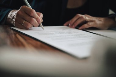İş kadınının belgeyi ya da sözleşmeyi imzaladığı düşük açılı yakın plan görüntüsü.