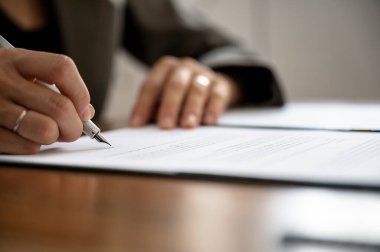 Kadın elinin, avukatın, sigortacının ya da iş kadınının yakın plan görüntüsü, bir belge imzalamak ya da mürekkep kalemi ile sözleşme imzalamak..