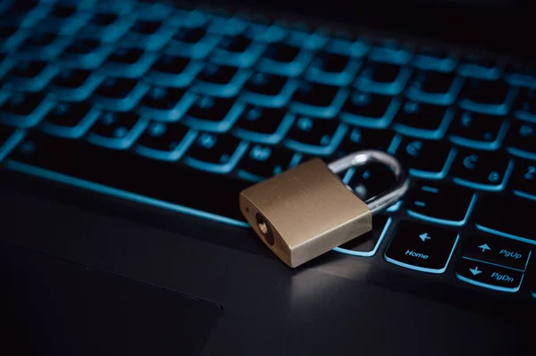 Golden locked padlock lying on a black laptop computer keyboard in a conceptual image of cyber security, firewall and data and passwork protection.