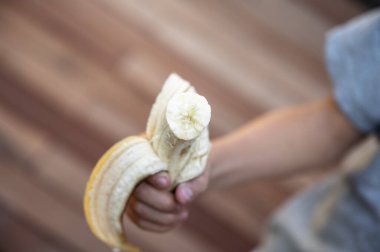 Elinde yarısı yenmiş bir muzu tutan bir çocuğun görüntüsü. 