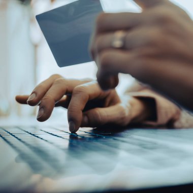 Diz üstü bilgisayar kullanan ve online alışveriş veya bankacılık yaparken kredi kartı tutan kadınların düşük açılı görüntüsü. 