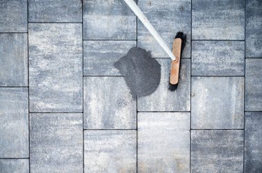 Avlu ya da kaldırım için yeni döşenmiş gri beton fayanslar arasındaki boşluklara doldurulmaya hazır kum yığınının üst görüntüsü. İnşaat ve yenileme projesi. 