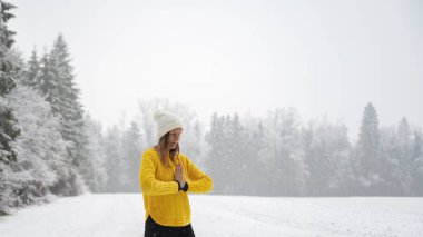 Parlak sarı kazaklı huzurlu genç bir kadın meditasyon yapıyor ya da avucu göğsünün önünde birleşmiş dua ediyor. Güzel, sakin bir karla kaplı kış doğası. Zihnin farkındalığı ve huzuru kavramsal imaj.