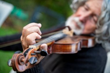Yakın plan bir müzisyen eli keman çalıyor, o anın sanatını ve tutkusunu yakalıyor. .