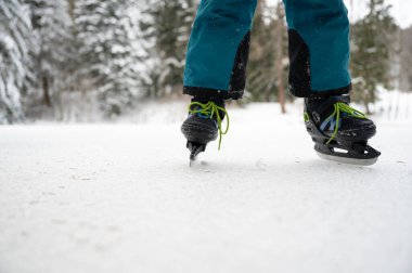 Düşük açılı, karlı doğada buzda buz pateni yapan bir çocuğun bacaklarının kapalı görüntüsü..