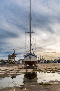 Kolobrzeg, Polonya - Ekim 2021: Eski bir feribot büyük su birikintisine yansıyan eski bir marinada duruyor