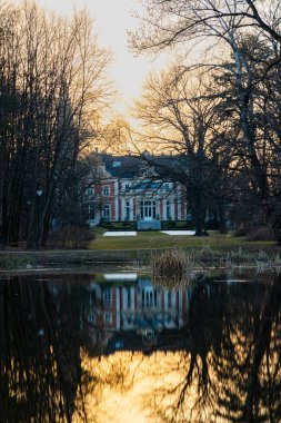 Wroclaw, Poland - March 2022: Palace in Pawlowice park at sunset reflected in small lake