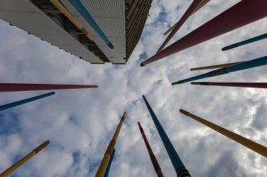 A lot of high colorful poles at kids playground next to modern estate