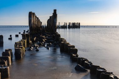 Beautiful landscape of coast of Baltic sea and old wooden breakwater at sunny cloudy morning