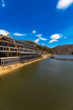 Zagorze Slaskie, Poland - April 2022: Beautiful landscape of Bystrzyckie lake and hills around seen from small footbridge over lake