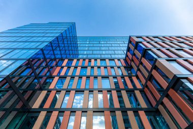 Wroclaw, Polonya - Haziran 2022: Cam pencereler, dekorasyonlar ve mavi gökyüzünü yansıtan yüksek ve modern ofis binası