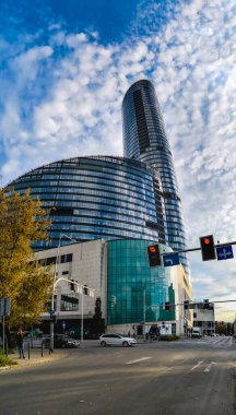 Wroclaw, Polonya - Ekim 2022: Modern cam gökdelen Gökdelen Gökdelen Binası 'nın güneşli ve bulutlu öğleden sonra evleri ve ofisleri olan dikey manzarası