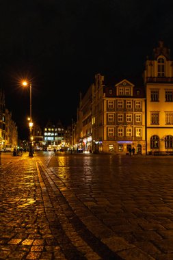 Wroclaw, Polonya - Ocak 2023: Yürüyen insanlar, parlayan fenerler ve güzel ve renkli yüksek noel ağacı ile pazar meydanı