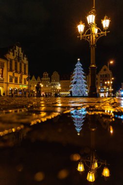 Wroclaw, Polonya - Ocak 2023: Yürüyen insanlar, parlayan fenerler ve güzel ve renkli yüksek noel ağacı ile pazar meydanı