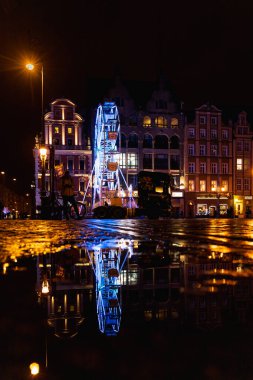 Wroclaw, Polonya - Ocak 2023: Renkli pazar meydanında gece su birikintisine yansıyan güzel ve renkli dönme dolap 