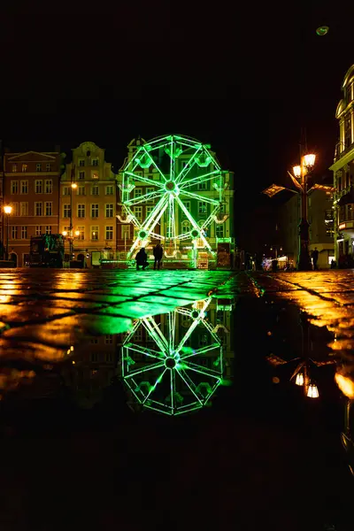 Wroclaw, Polonya - Ocak 2023: Renkli pazar meydanında gece su birikintisine yansıyan güzel ve renkli dönme dolap 