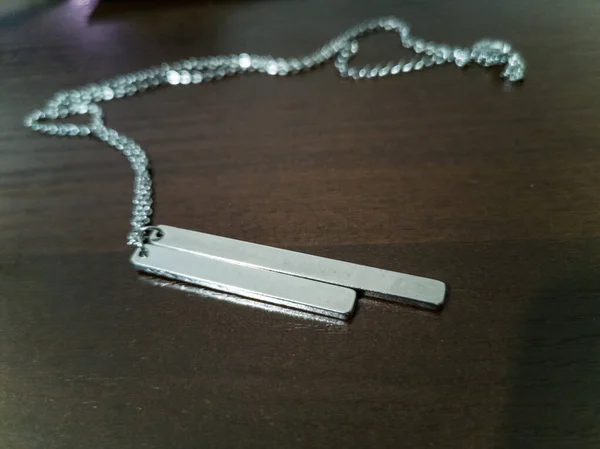 小银项链 上面刻有一个更长 一个更短的盘子和一条长长的小链子 — 图库照片