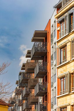 Wroclaw, Polonya - 15 Nisan 2023: Eski apartman bloğunun yanındaki dekoratif balkonlu modern binanın cephelerine bakış açısı