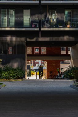 Wroclaw, Polonya - 15 Nisan 2023: Camdan balkonları ve içinde bisiklet sürücüleri olan küçük tünelleri olan modern apartman bloklarının karanlık cephesi
