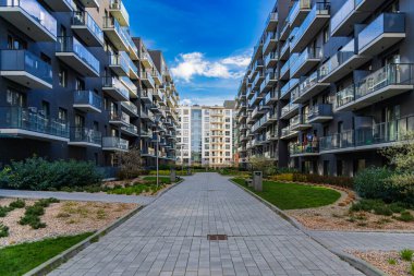 Wroclaw, Polonya - 15 Nisan 2023: Yeni modern malikanenin yansıtıcı cam balkonlarına sahip iki modern apartman bloğunun cepheleri arasında uzun tuğla yol