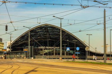 Lodz, Polonya - 21 Nisan 2023: Lodz Fabryczna tren istasyonunun modern ve endüstriyel cephesi bulutlu günbatımında