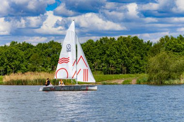 Wroclaw, Polonya - 14 Mayıs 2023: Bulutlu bir günde Odra nehrinde yeşil ağaçlar ve çalılarla yüzen Sagitta adlı küçük beyaz tekne