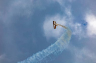 Leszno, Polonya - 16 Haziran 2023: Antidotum Airshow Leszno 2023 ve mavi bulutlu gökyüzünde sarı Boeing Stearman uçağı akrobatik gösterileri