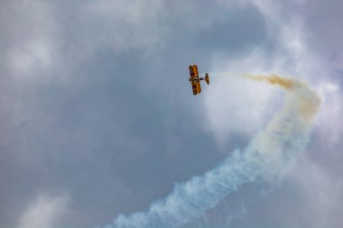 Leszno, Polonya - 16 Haziran 2023: Antidotum Airshow Leszno 2023 ve mavi bulutlu gökyüzünde sarı Boeing Stearman uçağı akrobatik gösterileri