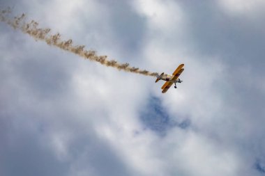 Leszno, Polonya - 16 Haziran 2023: Antidotum Airshow Leszno 2023 ve mavi bulutlu gökyüzünde sarı Boeing Stearman uçağı akrobatik gösterileri