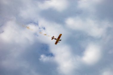 Leszno, Polonya - 16 Haziran 2023: Antidotum Airshow Leszno 2023 ve mavi bulutlu gökyüzünde sarı Boeing Stearman uçağı akrobatik gösterileri
