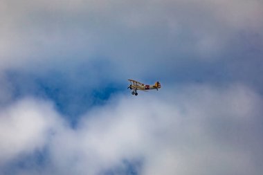 Leszno, Polonya - 16 Haziran 2023: Antidotum Airshow Leszno 2023 ve mavi bulutlu gökyüzünde sarı Boeing Stearman uçağı akrobatik gösterileri