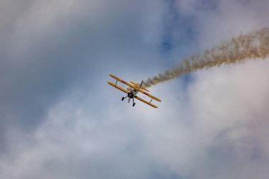 Leszno, Polonya - 16 Haziran 2023: Antidotum Airshow Leszno 2023 ve mavi bulutlu gökyüzünde sarı Boeing Stearman uçağı akrobatik gösterileri