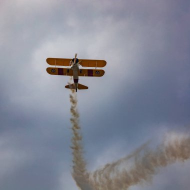 Leszno, Polonya - 16 Haziran 2023: Antidotum Airshow Leszno 2023 ve mavi bulutlu gökyüzünde sarı Boeing Stearman uçağı akrobatik gösterileri