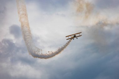 Leszno, Polonya - 16 Haziran 2023: Antidotum Airshow Leszno 2023 ve mavi bulutlu gökyüzünde sarı Boeing Stearman uçağı akrobatik gösterileri