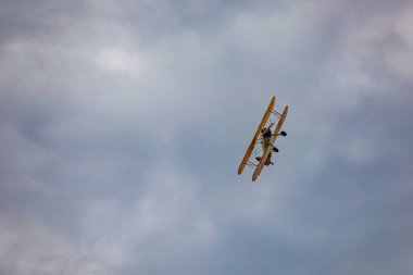 Leszno, Polonya - 16 Haziran 2023: Antidotum Airshow Leszno 2023 ve mavi bulutlu gökyüzünde sarı Boeing Stearman uçağı akrobatik gösterileri