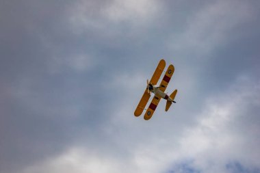 Leszno, Polonya - 16 Haziran 2023: Antidotum Airshow Leszno 2023 ve mavi bulutlu gökyüzünde sarı Boeing Stearman uçağı akrobatik gösterileri