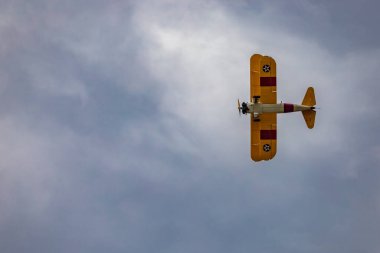 Leszno, Polonya - 16 Haziran 2023: Antidotum Airshow Leszno 2023 ve mavi bulutlu gökyüzünde sarı Boeing Stearman uçağı akrobatik gösterileri