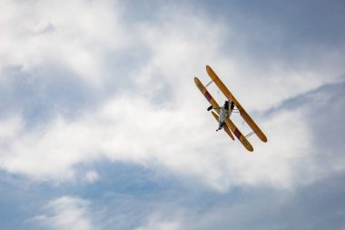 Leszno, Polonya - 16 Haziran 2023: Antidotum Airshow Leszno 2023 ve mavi bulutlu gökyüzünde sarı Boeing Stearman uçağı akrobatik gösterileri