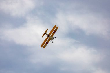 Leszno, Polonya - 16 Haziran 2023: Antidotum Airshow Leszno 2023 ve mavi bulutlu gökyüzünde sarı Boeing Stearman uçağı akrobatik gösterileri